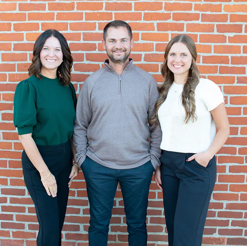The founders of Freebird standing together in front of a brick wall
